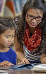 Young teacher instructing a smaller group of elementary students on reading