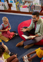 A young teacher reads aloud a picture book to children