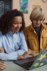 A young teacher teaches her elementary students using a laptop
