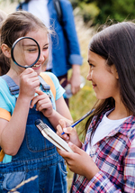 Young elementary students outside exploring with a teacher
